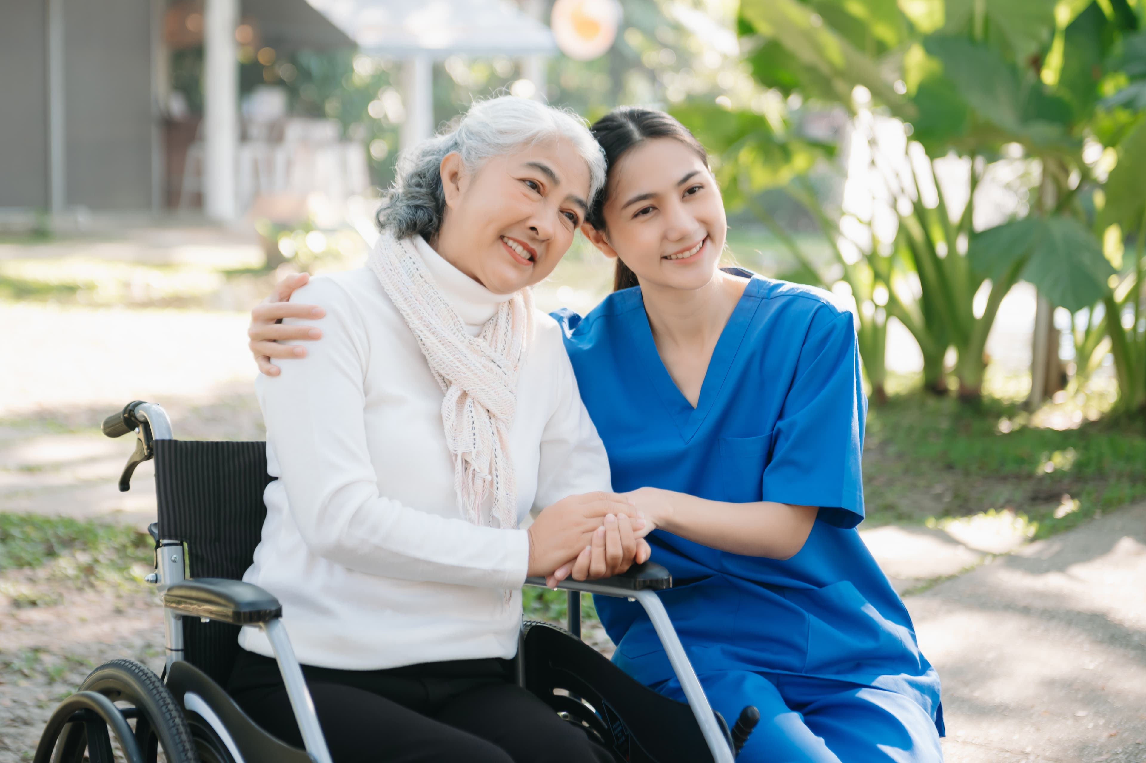 Caring nurse embracing a senior woman in a wheelchair