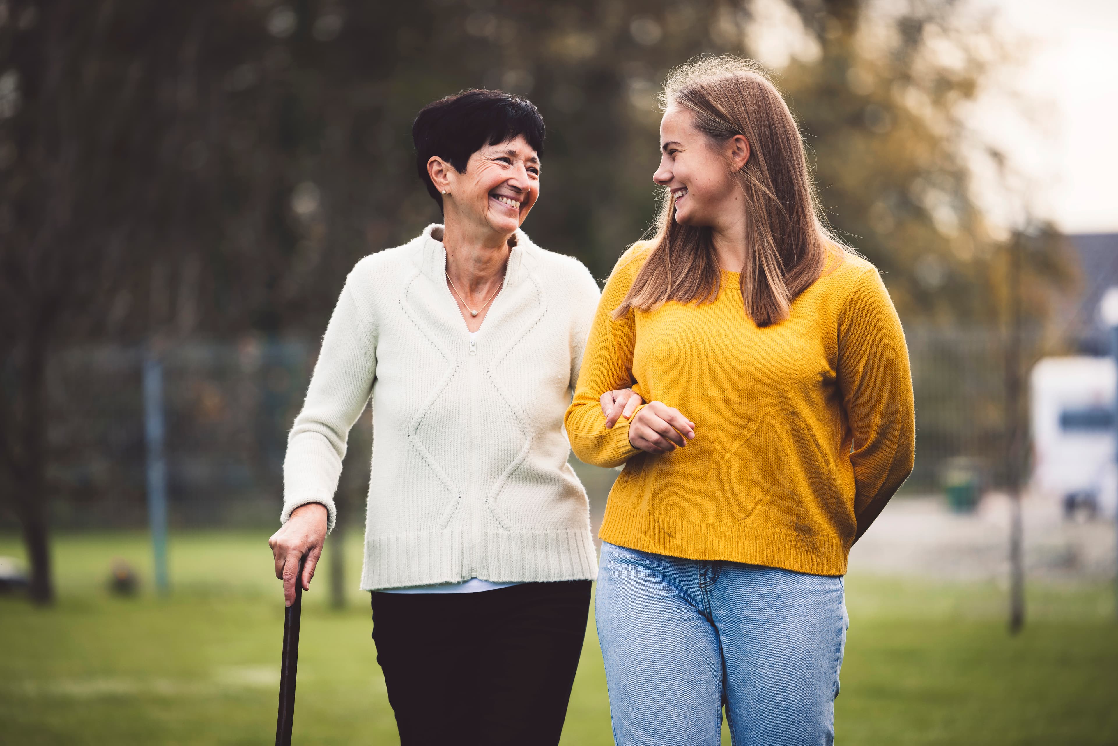 Senior and carer walking together outdoors